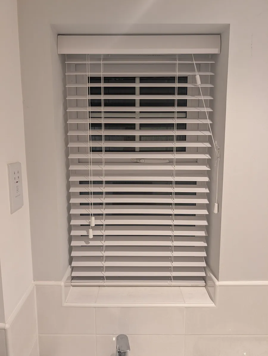 White venetian blind fitted in a tiled bathroom window recess